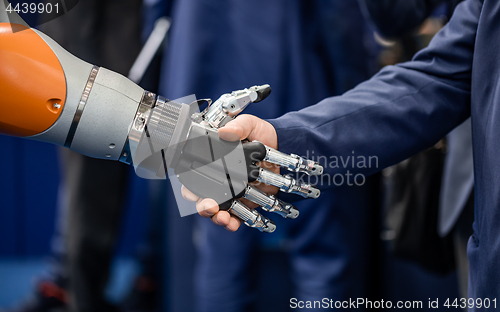 Image of Hand of a businessman shaking hands with a Android robot.