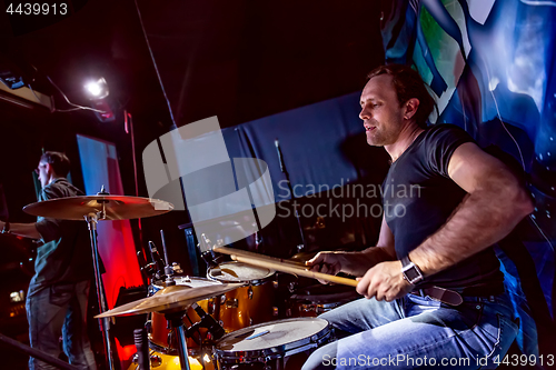 Image of Drummer playing on drum set on stage.