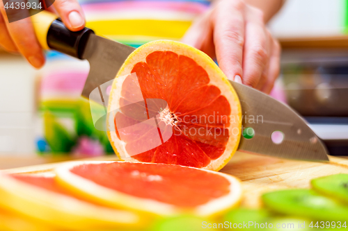 Image of Women\'s hands Housewives cut with a knife fresh grapefruit on th