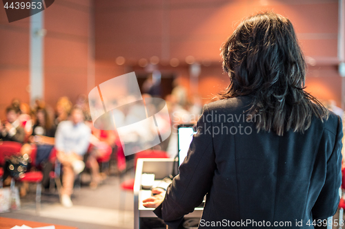 Image of Female public speaker giving talk at Business Event.