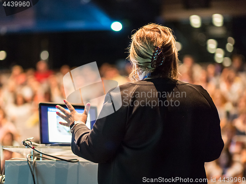 Image of Female public speaker giving talk at Business Event.