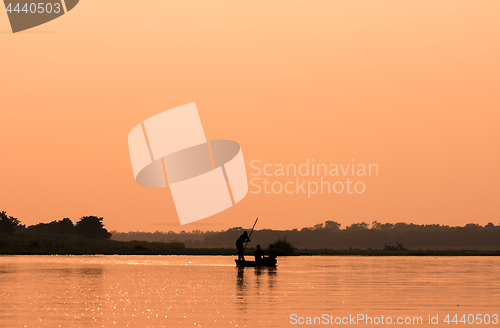 Image of Men in a boat on a river silhouette