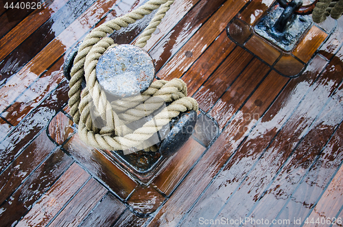 Image of Bollard with a rope on the wooden deck of a sailing vessel, clos