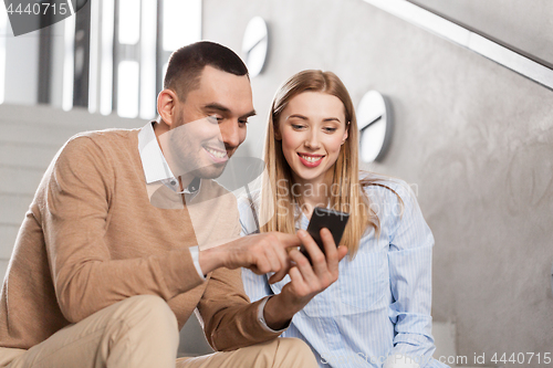 Image of man and woman with smartphone at office stairs