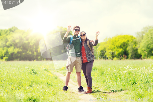 Image of happy couple with backpacks hiking outdoors