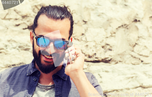 Image of smiling man with smartphone calling on city street