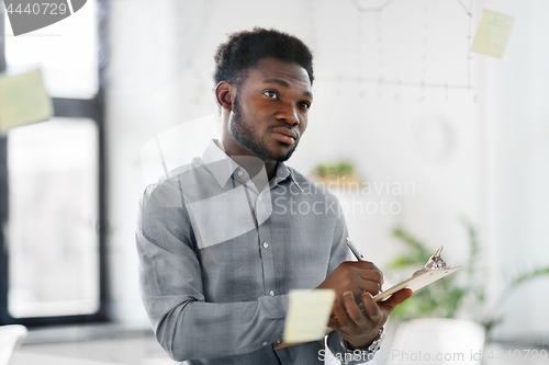 Image of businessman with clipboard at office glass wall