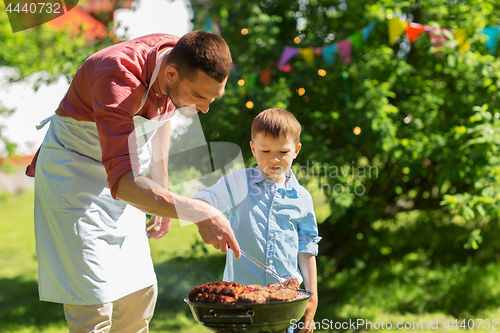 Image of father and son cooking meat on barbecue grill