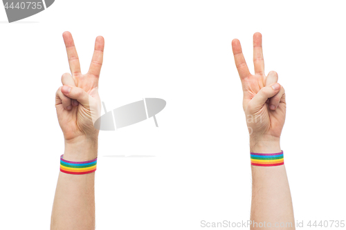 Image of hands with gay pride rainbow wristbands make peace