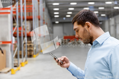 Image of businessman with smartphone at warehouse