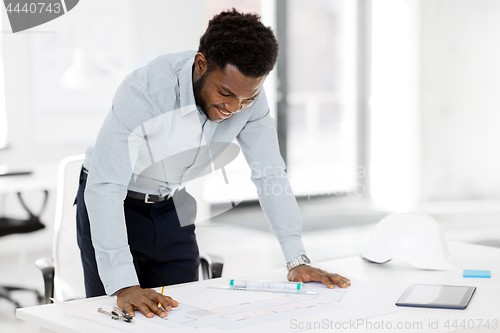 Image of smiling african architect with blueprint at office