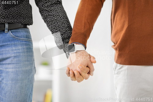 Image of close up of male gay couple hands with smart watch