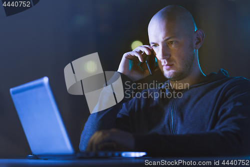 Image of hacker with laptop calling on cellphone