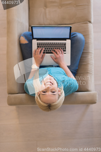 Image of Young woman using laptop at home top view