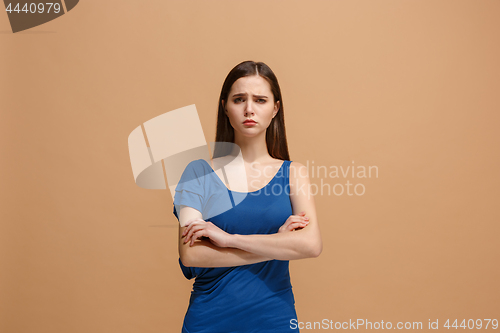 Image of The sad woman standing and looking at camera against pastel background.