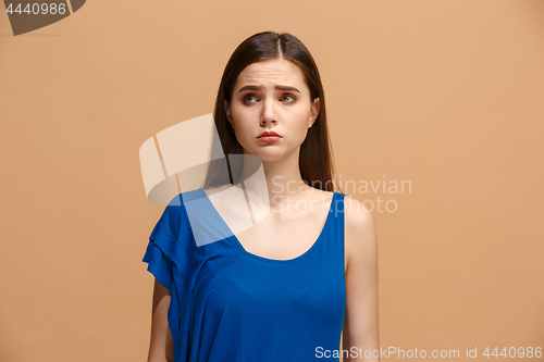 Image of The awkward woman standing and looking at camera against pastel background.