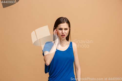 Image of The Ear ache. The sad woman with headache or pain on a pastel studio background.