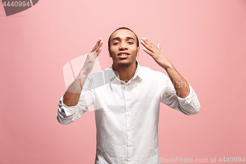 Image of Beautiful male half-length portrait isolated on pink studio backgroud. The young emotional surprised man