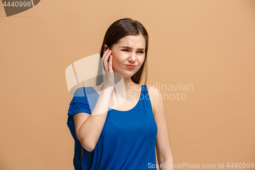 Image of The Ear ache. The sad woman with headache or pain on a pastel studio background.