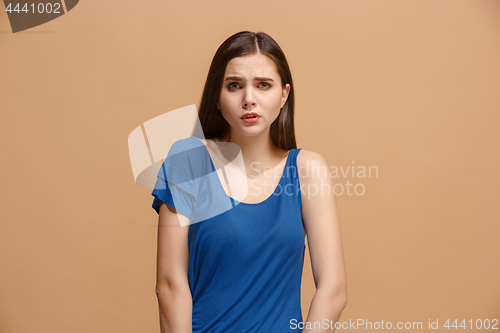 Image of The awkward woman standing and looking at camera against pastel background.