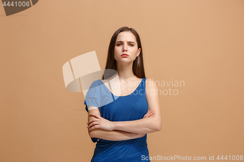 Image of The serious woman standing and looking at camera against pastel background.
