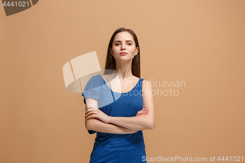 Image of The serious woman standing and looking at camera against pastel background.