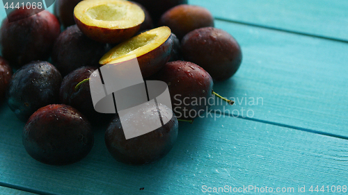 Image of Purple plums on blue wood