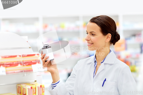 Image of happy female apothecary with drug at pharmacy