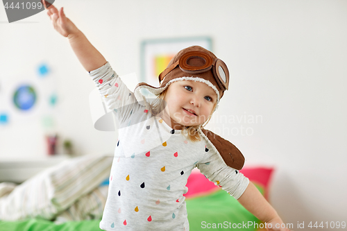 Image of happy little girl in pilot hat playing at home