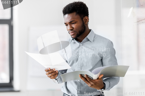 Image of african american businessman with folder at office