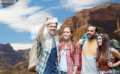 Image of friends with backpack taking selfie by smartphone