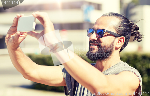 Image of man taking video or selfie by smartphone in city