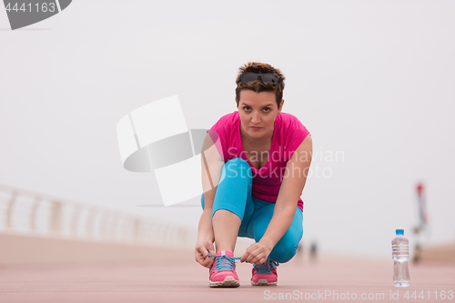 Image of Young woman tying shoelaces on sneakers