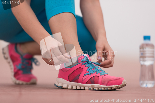 Image of Young woman tying shoelaces on sneakers