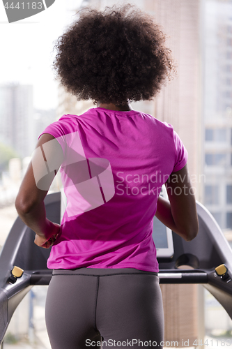 Image of afro american woman running on a treadmill