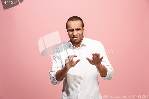 Image of Young man with disgusted expression repulsing something, isolated on the pink