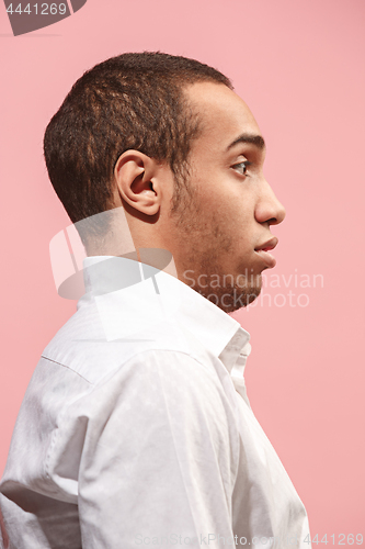 Image of The young attractive man looking suprised isolated on pink