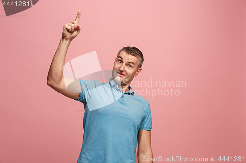 Image of The young attractive man looking suprised isolated on pink