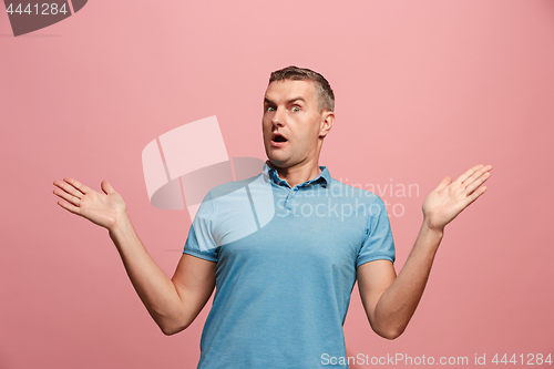 Image of The young attractive man looking suprised isolated on pink