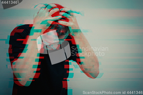 Image of one sad man standing near a  wall and covers his face
