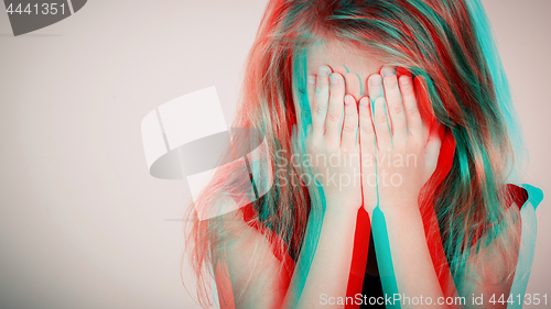 Image of Portrait of sad blond little girl sitting near wall