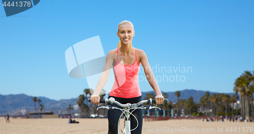 Image of happy young woman riding bicycle outdoors