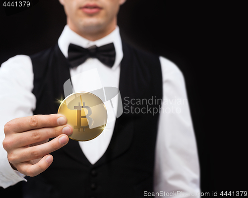 Image of close up of casino dealer holding bitcoin 