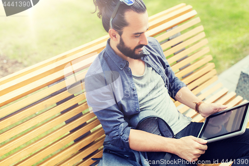 Image of man with tablet pc sitting on city street bench