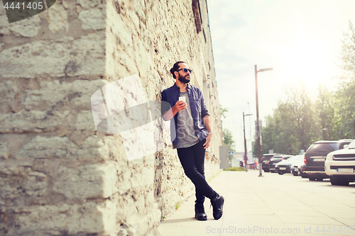 Image of man with smartphone at stone wall on city street