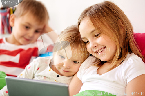 Image of happy little kids with tablet pc in bed at home