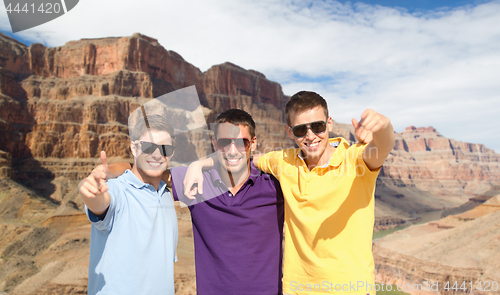 Image of group of male friends hugging over grand canyon