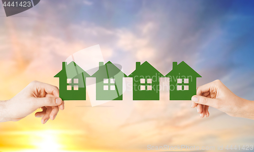 Image of man and woman hands with many green paper houses