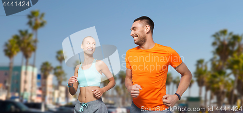 Image of smiling couple jogging at summer over venice beach