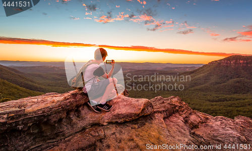 Image of Male hiker or bushwalker taking photos of the sunset